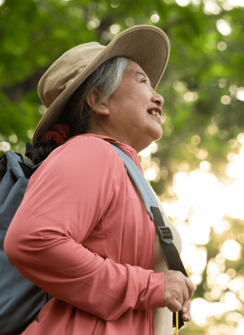 Senior woman in a backpack, a pink jacket and and a hat